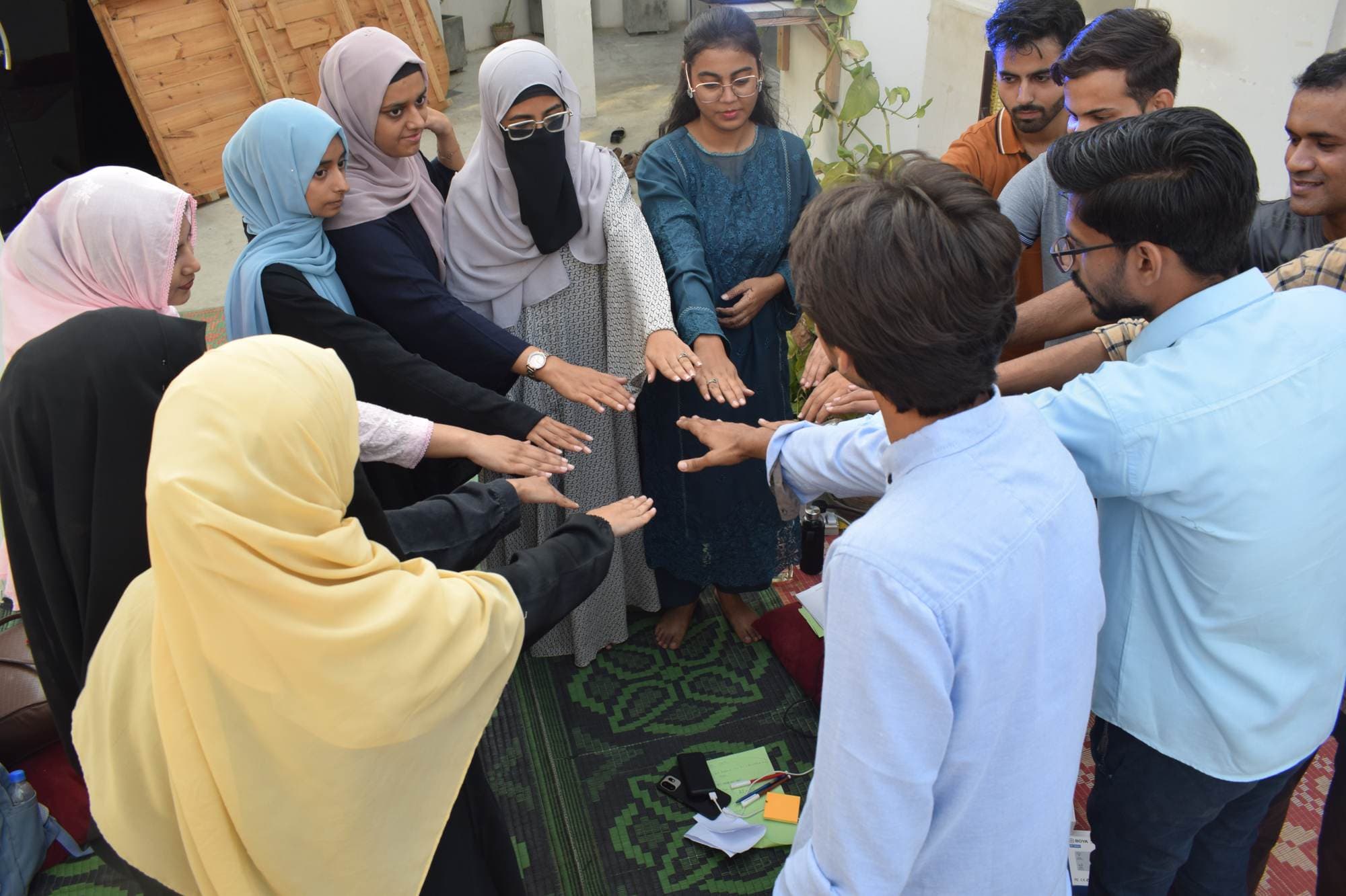 Attendees standing in a close circle with their hands together in the middle at Session 2