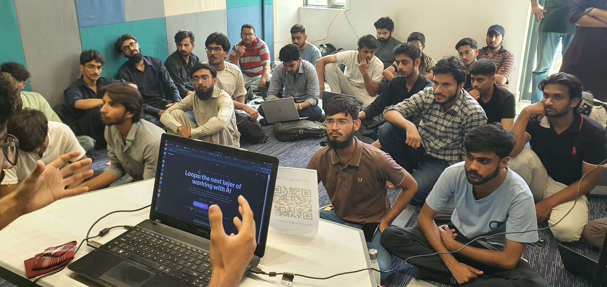 Attendees seated close together around an open laptop at Session 4